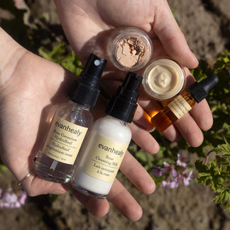 Hands holding evanhealy skincare products from the Ritual Kits collection outdoors