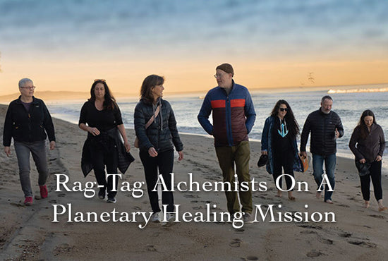 Group of people walking along a beach at sunset with overlaid text ‘Rag-Tag Alchemists On A Planetary Healing Mission’