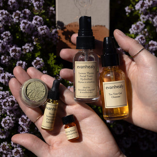Close-up of Purifying Starter skincare set showcasing facial tonic, gel cleanser, serum, and botanical treatments in hands