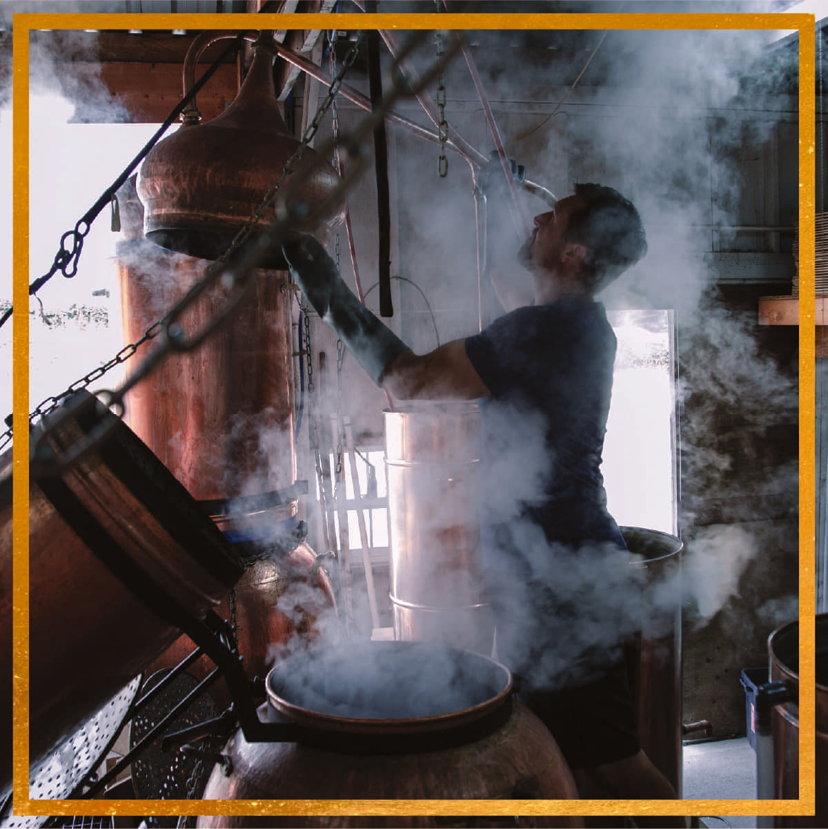 Distiller adjusting a copper alembic still as steam rises inside a rustic barn distillery