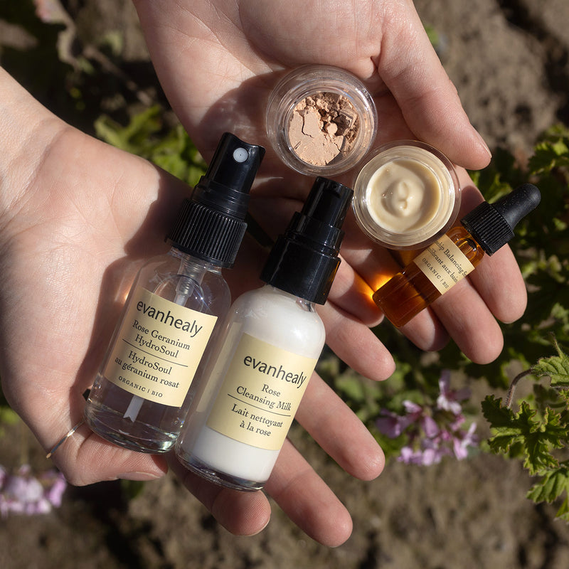 Hands holding evanhealy skincare products from the Ritual Kits collection outdoors