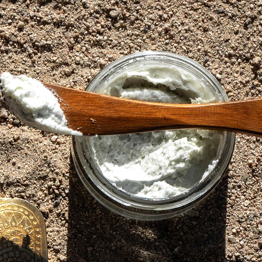 Top view of Whipped Blue Cactus Body Butter showcasing its whipped texture in an open jar with a wooden spatula