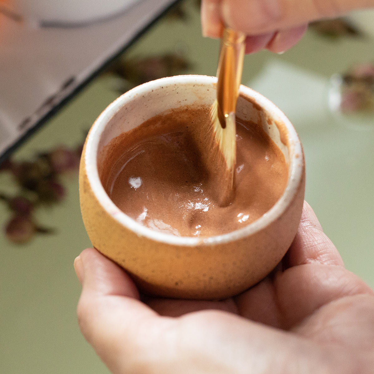 creamy texture of french rose clay mask and hydrosol mixed in handcrafted bowl with fan brush