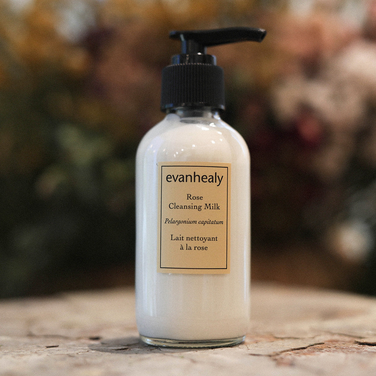 Front view of Rose Cleansing Milk showcasing its pump bottle and label with a softly blurred background