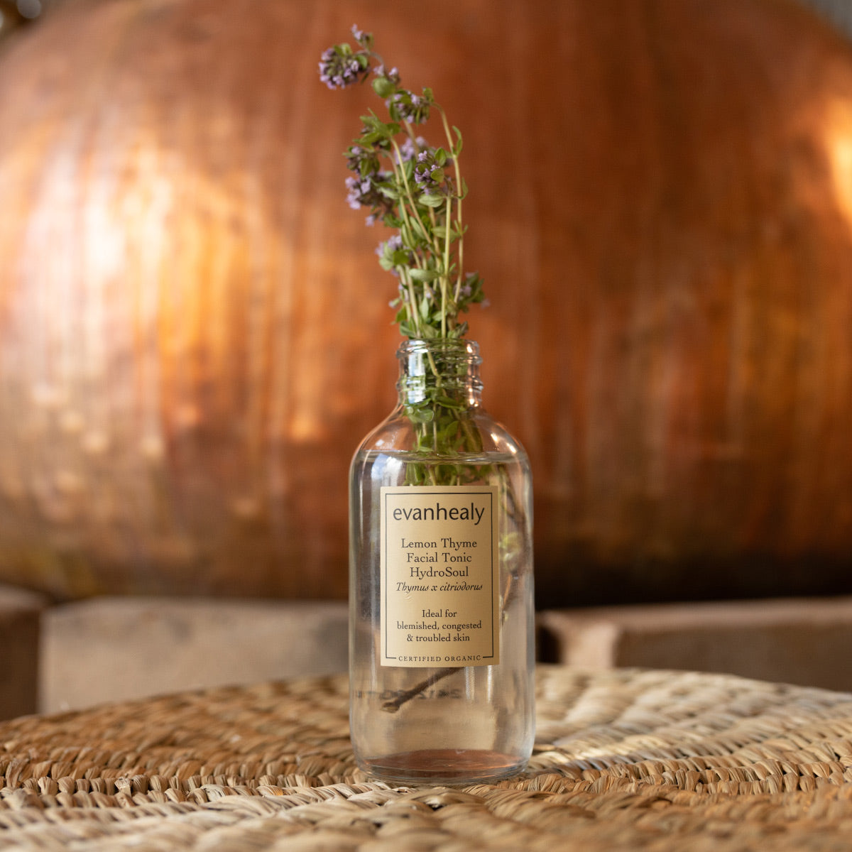 Front view of Lemon Thyme Facial Tonic HydroSoul showcasing thyme sprigs in a glass bottle with a rustic wooden background