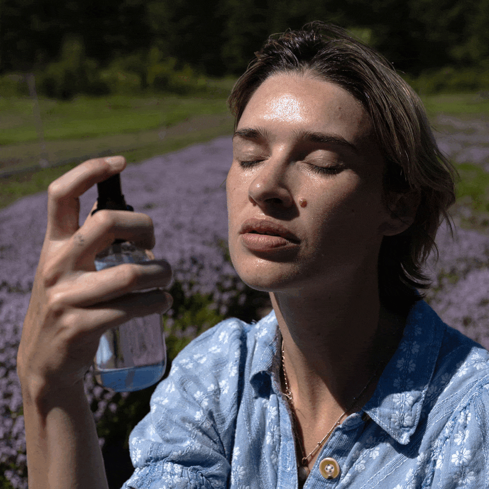 Woman sprays Lemon Thyme HydroSoul facial toner on her face outdoors in a lavender field