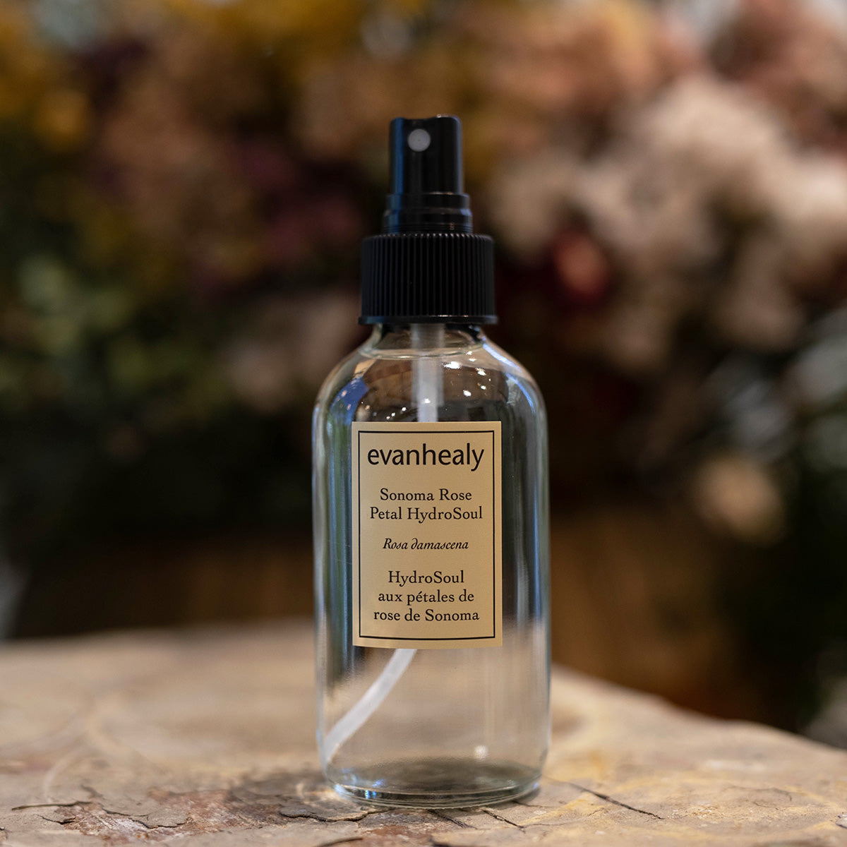 Front view of Sonoma Rose Petal HydroSoul bottle showcasing its spray pump with a blurred floral background