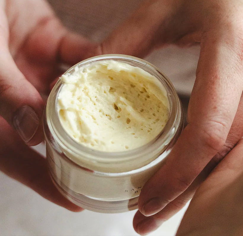 Close-up of Sanctuary Boswellia Butter jar showcasing its creamy texture with hands holding it