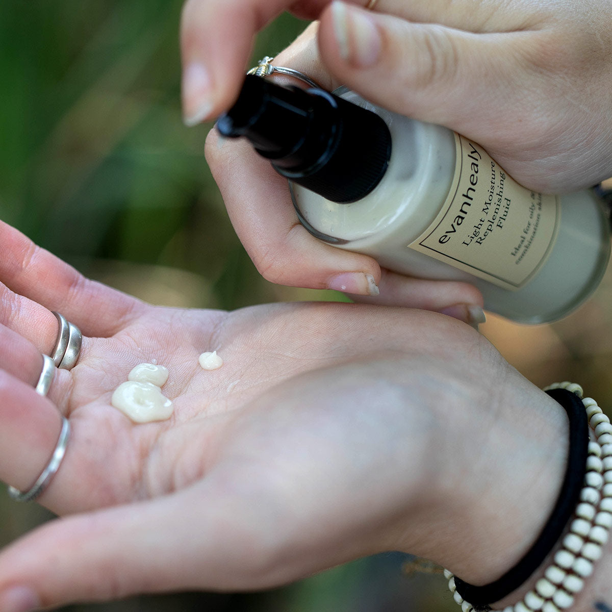 A person dispenses Lavender Argan Light Moisturizer into an open palm
