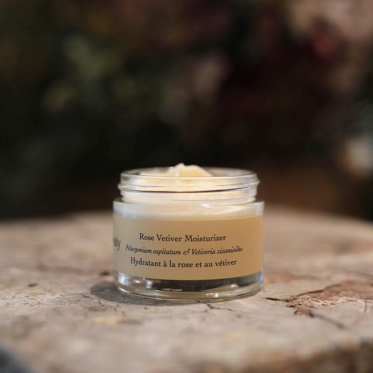 Front view of Rose Vetiver Moisturizer jar showcasing its open cream-filled container on a stone surface