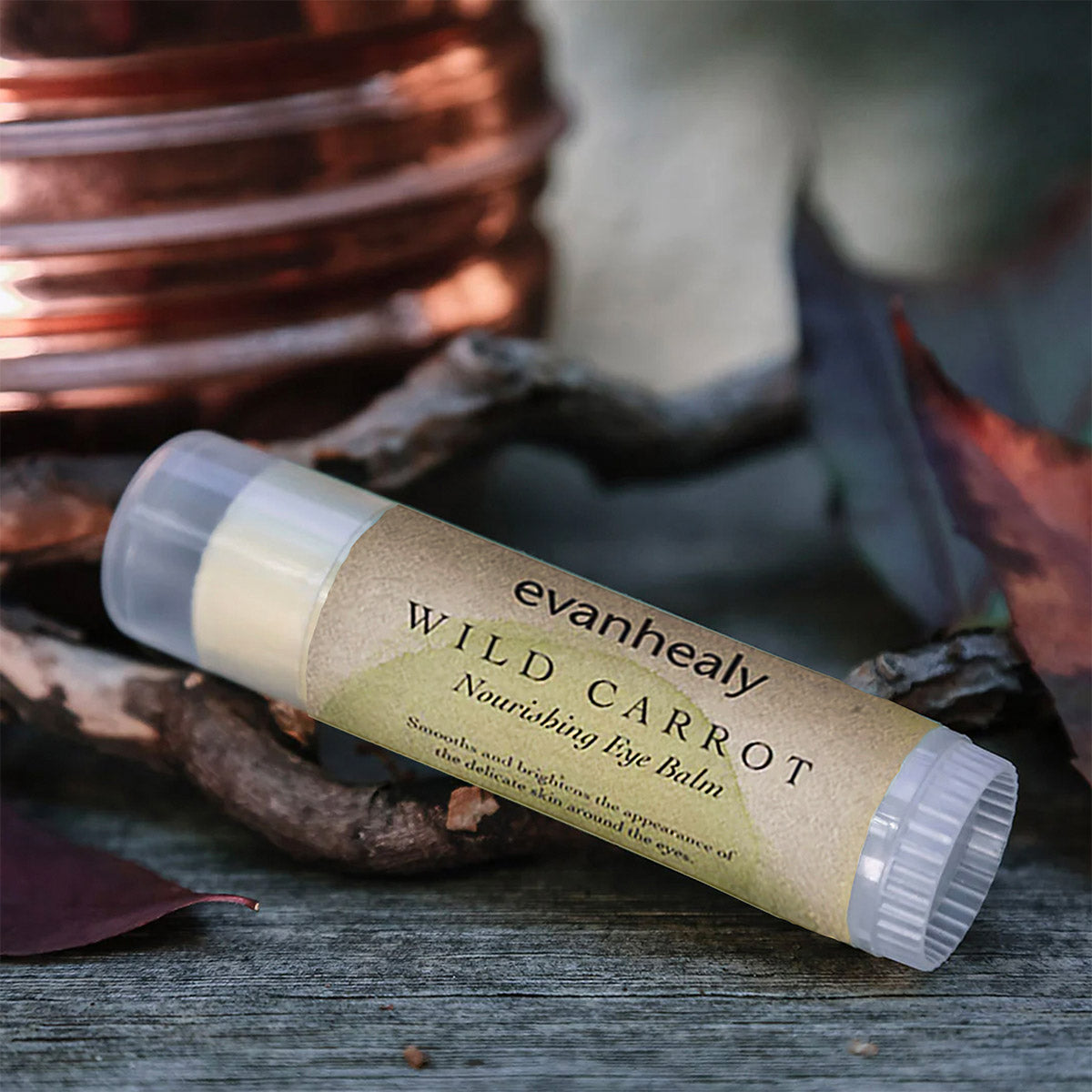 Angled view of Wild Carrot Immortelle Eye Balm showcasing its tube packaging on a dark wooden surface