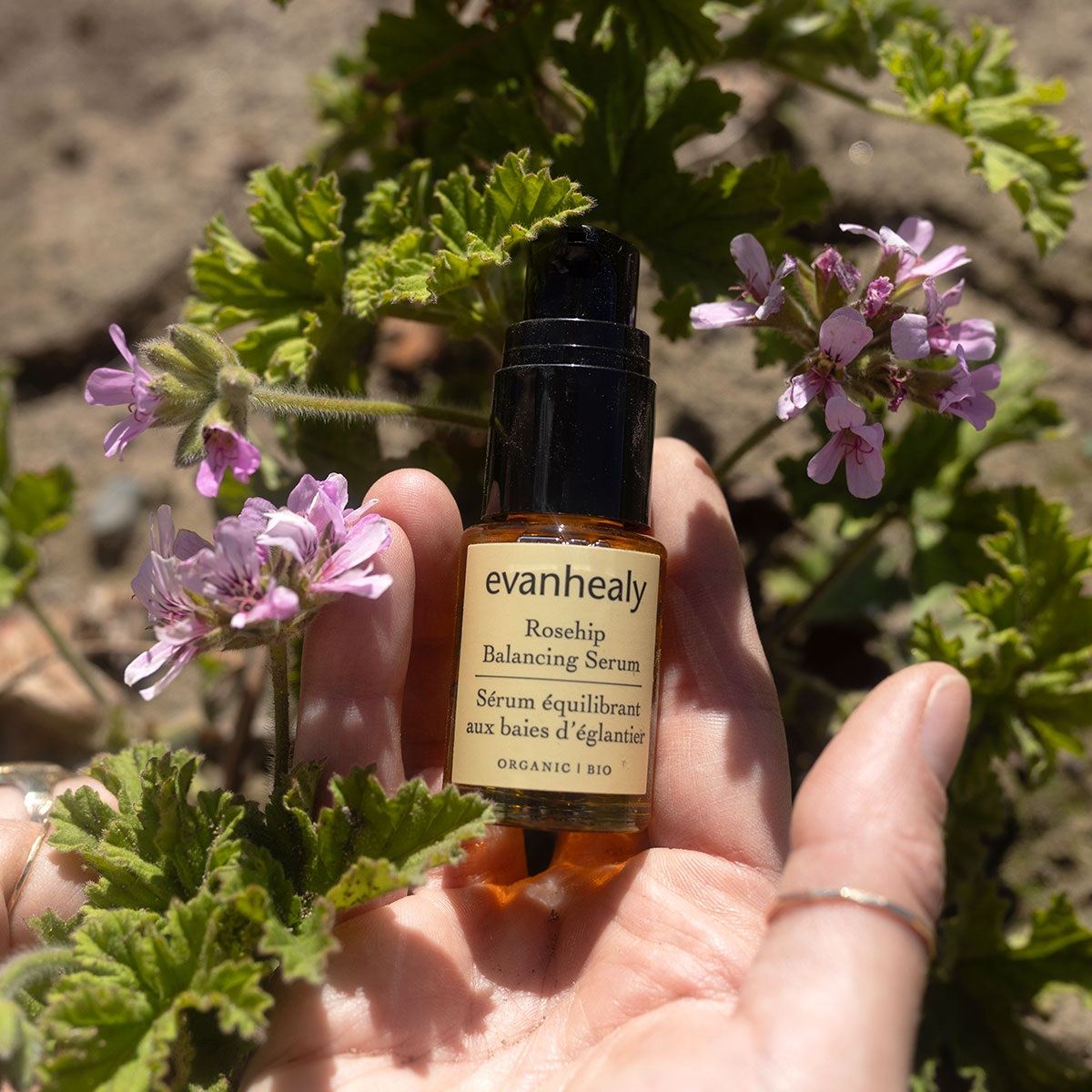 Front view of Rosehip Rose Balancing Facial Oil Serum bottle showcasing its label with botanical flowers in hand