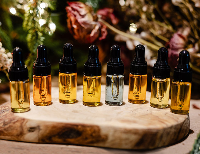 Travel-size oil bottles arranged on a wooden stand with festive greenery