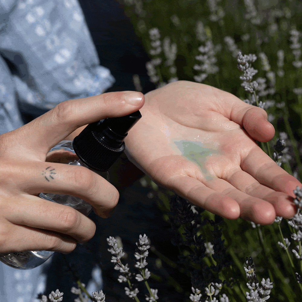 Person sprays skincare product into an open palm outdoors
