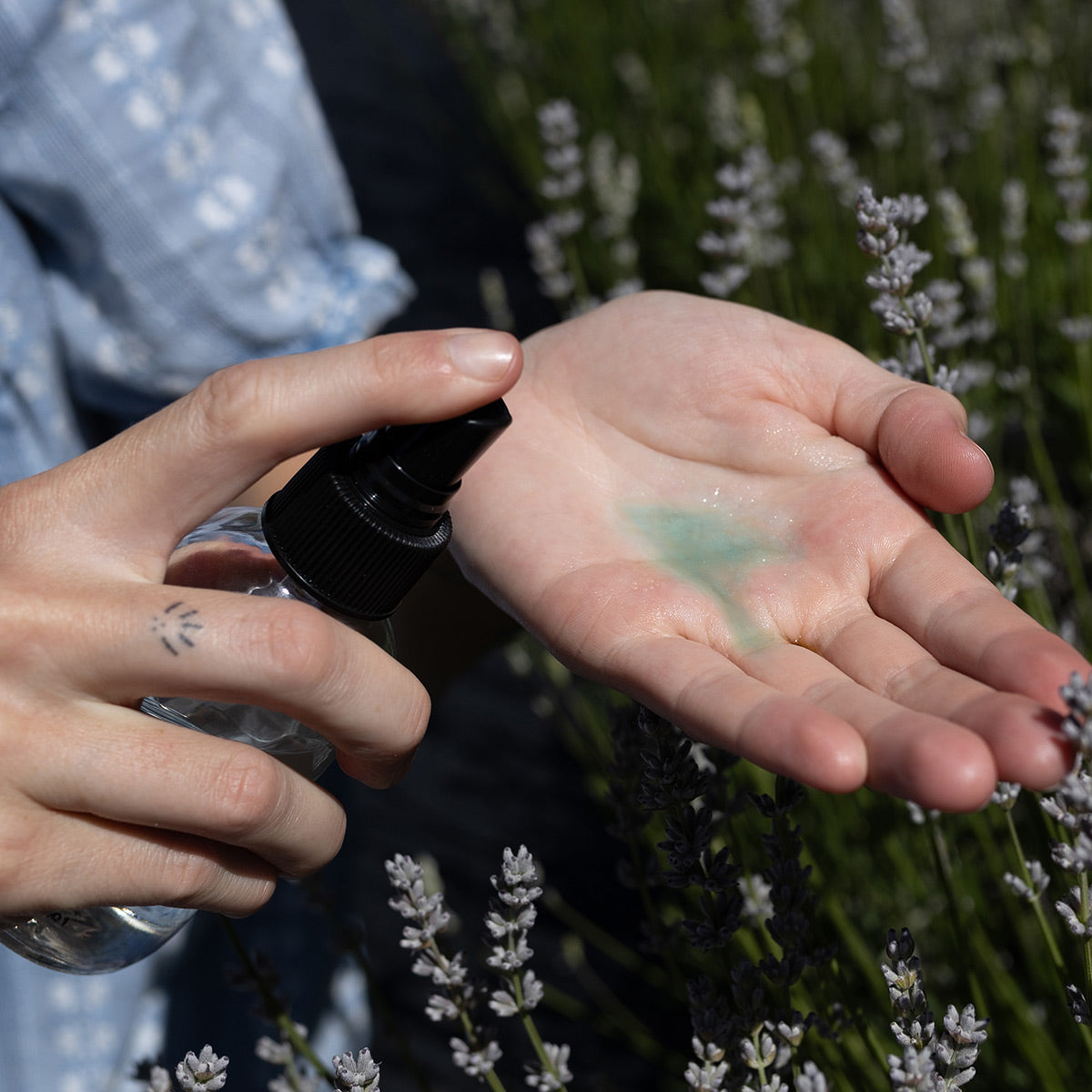 Blue Cactus Beauty Elixir dispensed into an open hand among lavender flowers