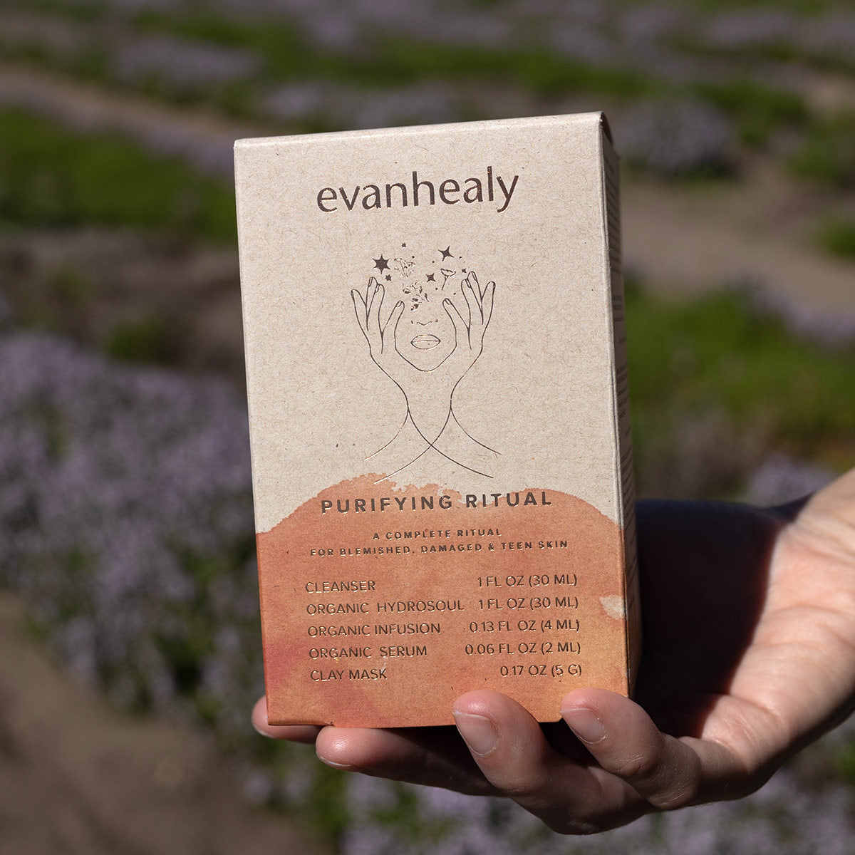 Front view of evanhealy Purifying Starter box labeled Purifying Ritual for blemished, damaged and teen skin, held outdoors