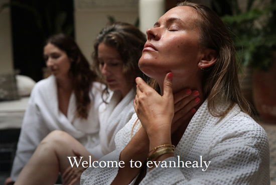 Woman in a white robe touching her neck with eyes closed in a spa, two women blurred behind, overlay text Welcome to evanhealy