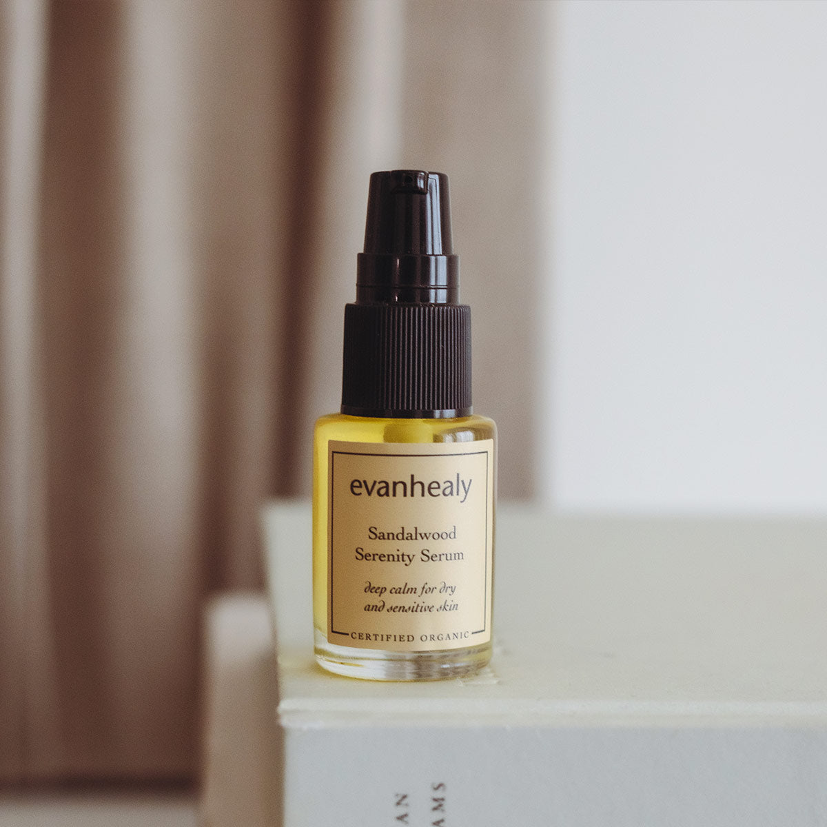 sacred sandalwood oil serum for face on top of a stack of books