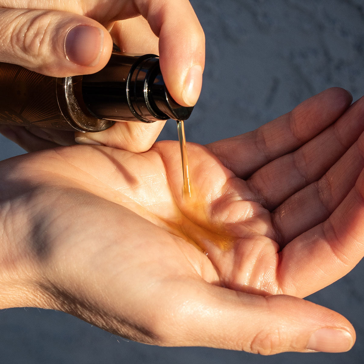 Hands dispensing Balm of Gilead Elixir into an open palm