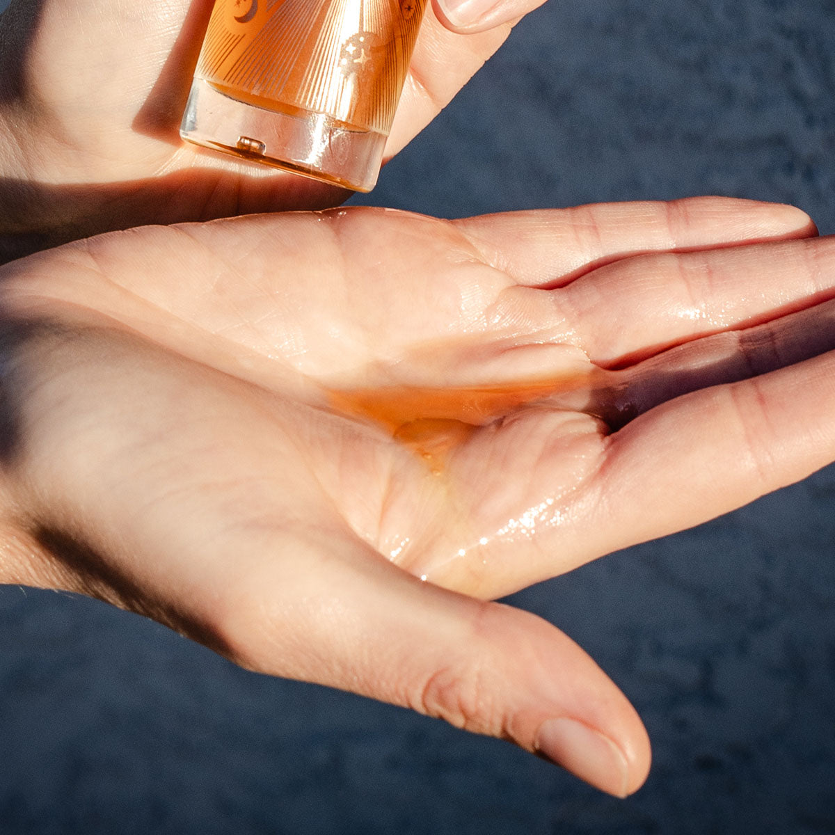 Close-up of Balm of Gilead Elixir showcasing its oil texture on an open palm with bottle visible