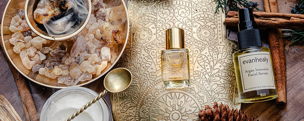 Evanhealy Argan Intensive Facial Serum and perfume bottle on a gold tray with frankincense resin, spoon, and cinnamon sticks