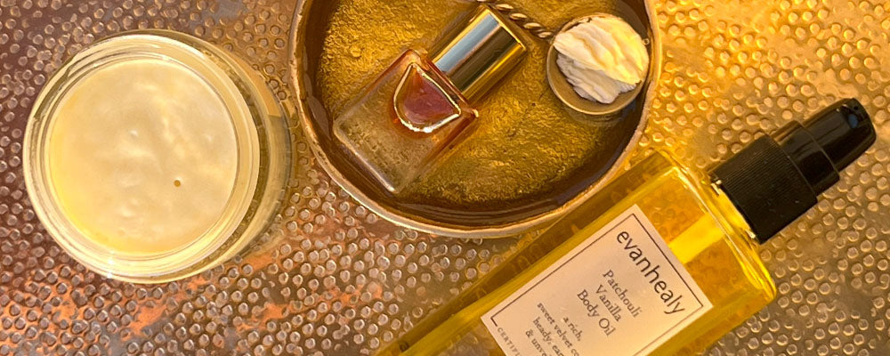Evanhealy Patchouli Vanilla body oil bottle beside jar of cream and small vial on hammered copper tray in warm light