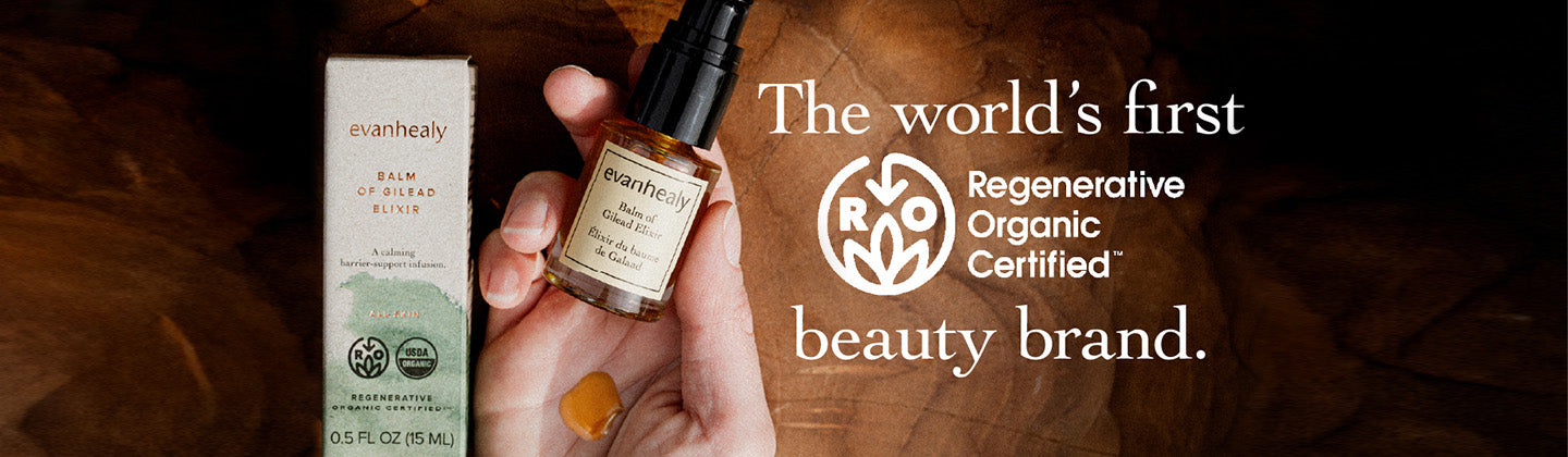 Hand holding amber oil bottle and box with a drop on wood background, overlay text Regenerative Organic Certified beauty brand