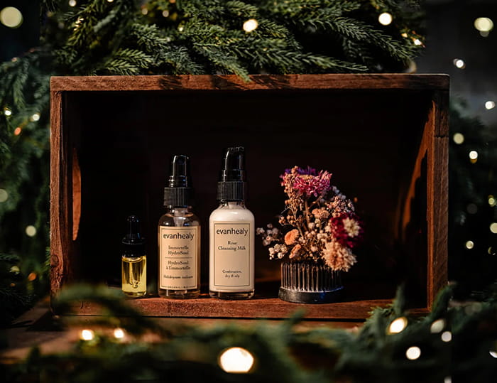 Small Reset Mini Ritual skincare set with three bottles in a wooden box, surrounded by holiday greenery and dried flowers