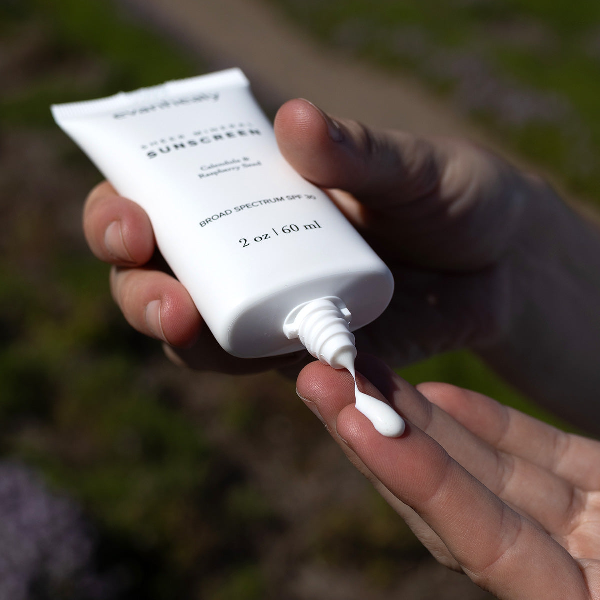 Close-up of Sheer Mineral Sunscreen dispensing onto a fingertip, labeled Broad Spectrum SPF 30 and 2 oz 60 ml