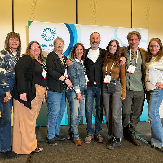 Eight evanhealy team members posing together at a trade show booth