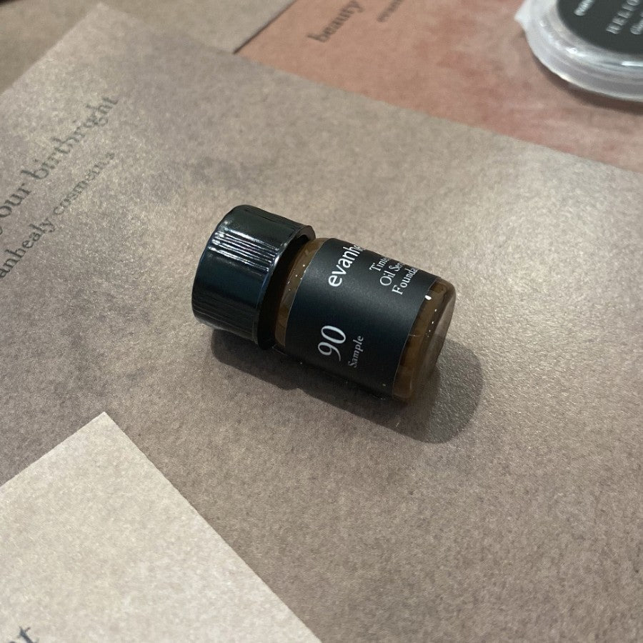 Small amber oil foundation sample bottle with a black cap and black label