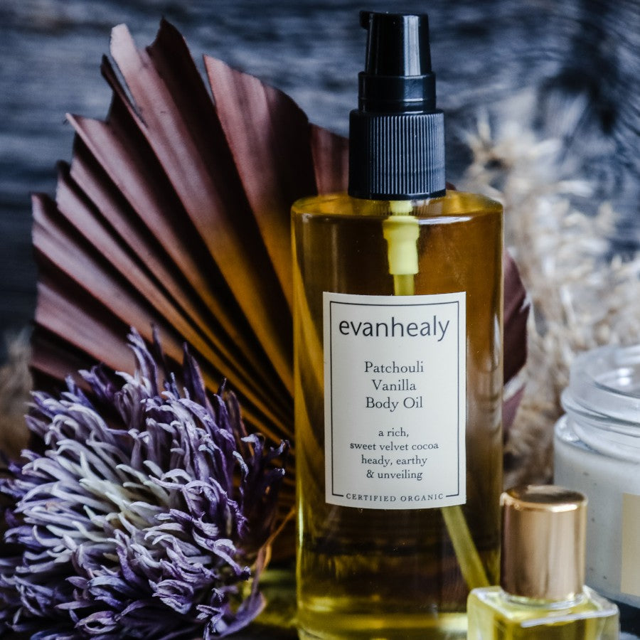 Front view of Patchouli Vanilla Body Oil showcasing its amber pump bottle with dried botanicals