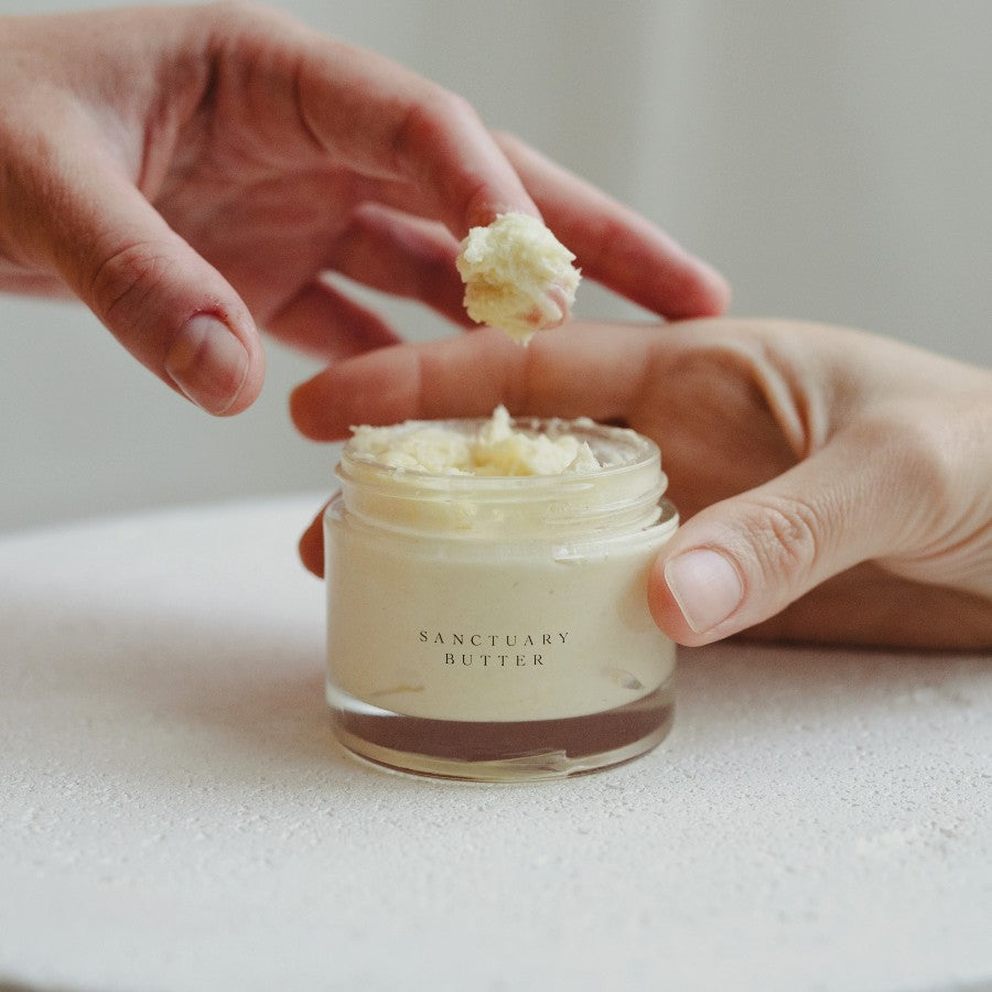 Close-up of Sanctuary Boswellia Butter showing creamy texture being scooped from an open jar with hands