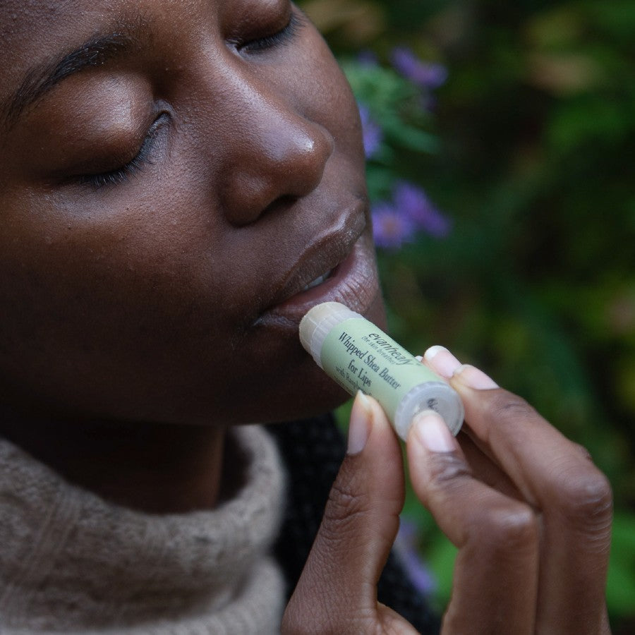 model applying shea butter chapstick lip balm to lips